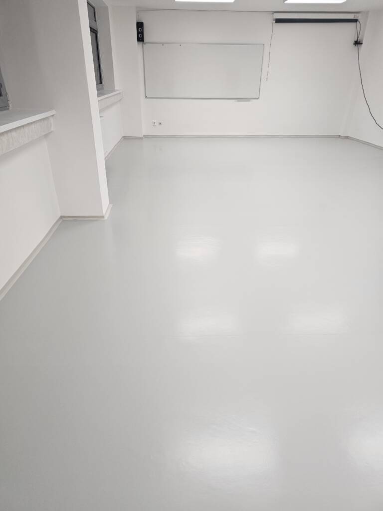 Hotová podlaha učebne, pohľad pozdĺž steny s tabuľou.
